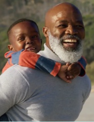 An older black man and a young black kid smiling happily