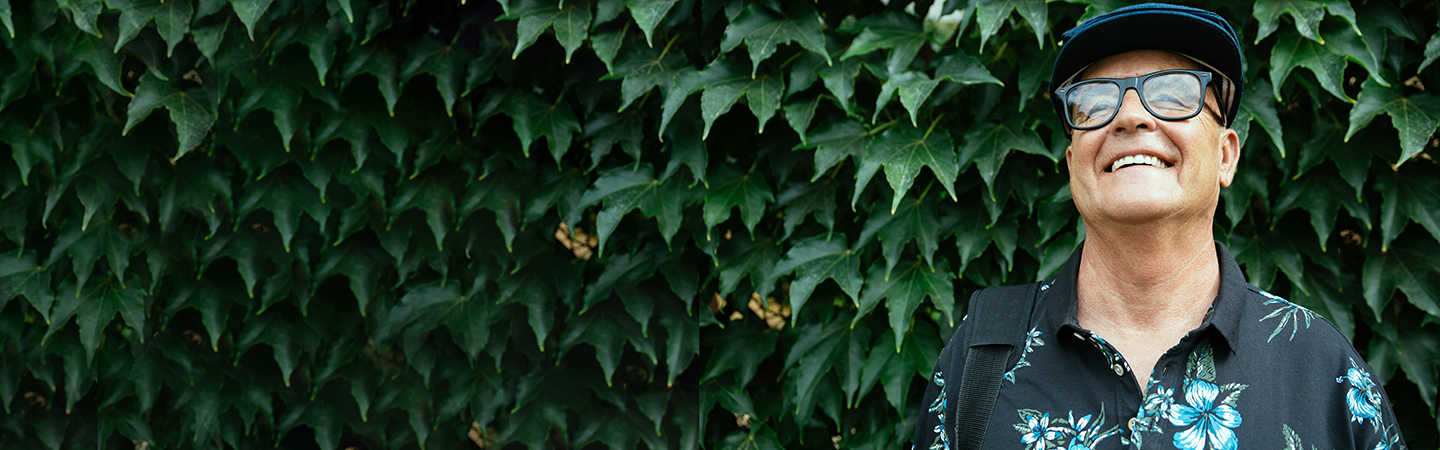 older man smiling in front of ivy