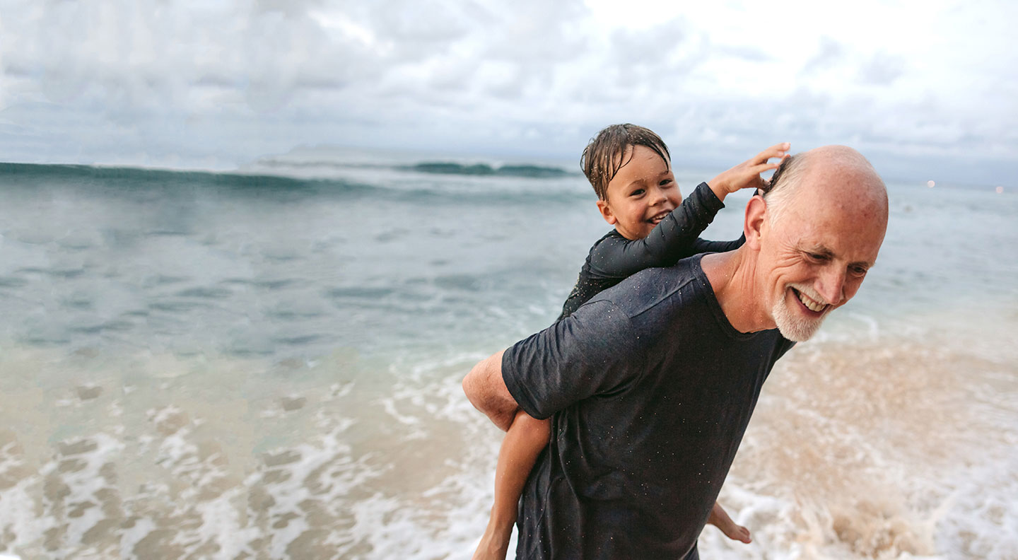 senior and child playing on the beach